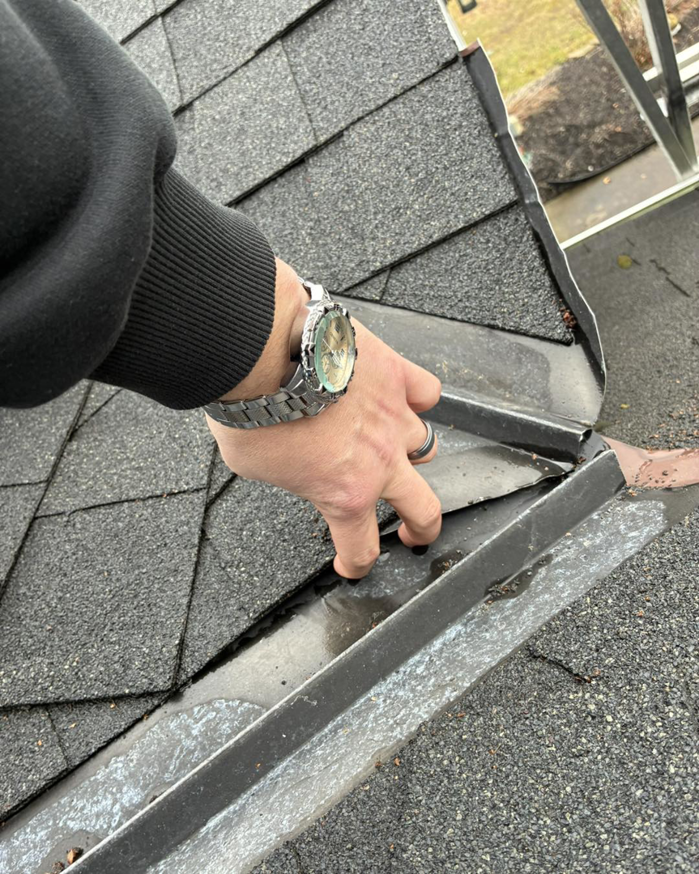 A hand inspecting damaged gutter and roof flashing, a common source of water leaks, by Barbera Home Improvement in Parma, OH.