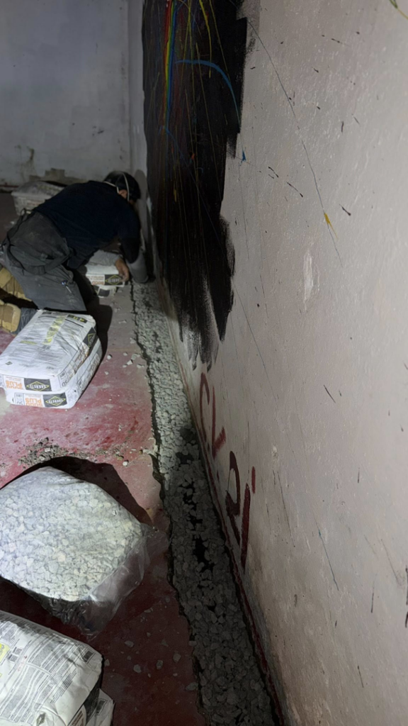 A specialist installing a basement drainage system with gravel for Tidewater Home Improvement LLC in Hampton, VA.