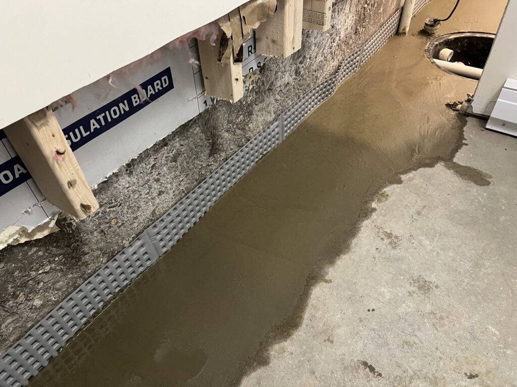 Interior basement waterproofing with a dimpled membrane and fresh concrete by EFFECTIVE WATERPROOFING in Worcester, MA.