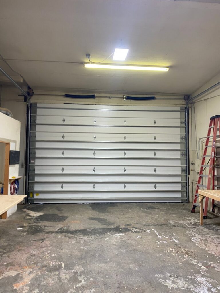 Interior view of a garage showing a newly installed white commercial-style garage door by Garage Door Store Boise, ID.