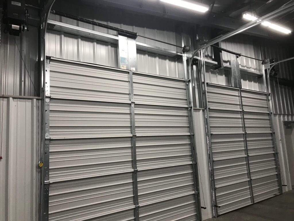 Interior view of two commercial garage doors with tracks and openers installed by Up N Over Garage Doors LLC in Layton, UT.