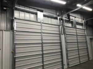 Interior view of two commercial garage doors with tracks and openers installed by Up N Over Garage Doors LLC in Layton, UT.