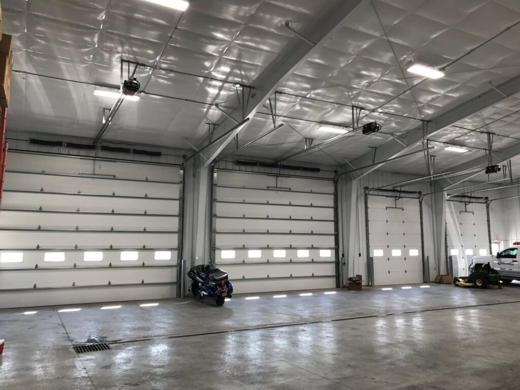 Interior view of a commercial building with multiple white overhead garage doors installed by Elite Door in Winchester, CA.