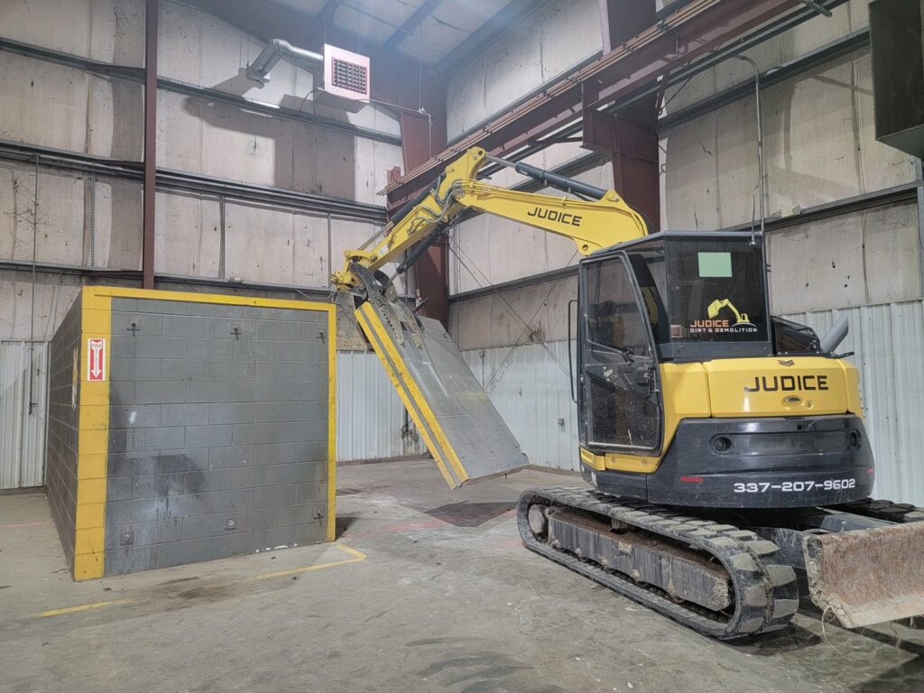 An excavator from Judice Dirt & Demolition moving a large concrete block during an interior demolition project in Lafayette, LA.