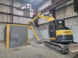 An excavator from Judice Dirt & Demolition moving a large concrete block during an interior demolition project in Lafayette, LA.