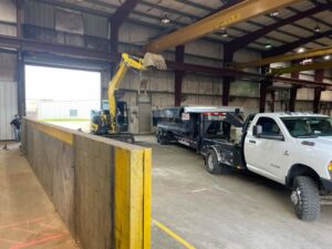 An excavator from Judice Dirt & Demolition removing interior demolition debris into a trailer inside a warehouse in Lafayette, LA.