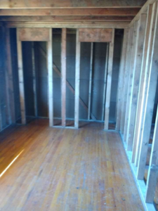Interior demolition showing exposed wooden framing and studs in a room, completed by Building Assisting Group Demolition INC in Tacoma, WA.