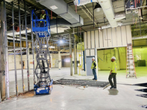 Interior demolition with exposed framing, worker on lift, and debris by Orion Demolition & Environmental Services, LLC in Albany, NY.