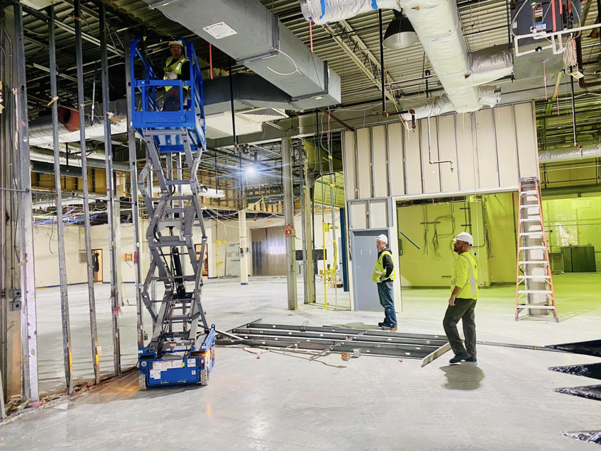 Interior demolition with exposed framing, worker on lift, and debris by Orion Demolition & Environmental Services, LLC in Albany, NY.