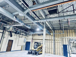 Interior demolition site with exposed ducts, wall studs, and a skid steer by Orion Demolition & Environmental Services, LLC in Albany, NY.