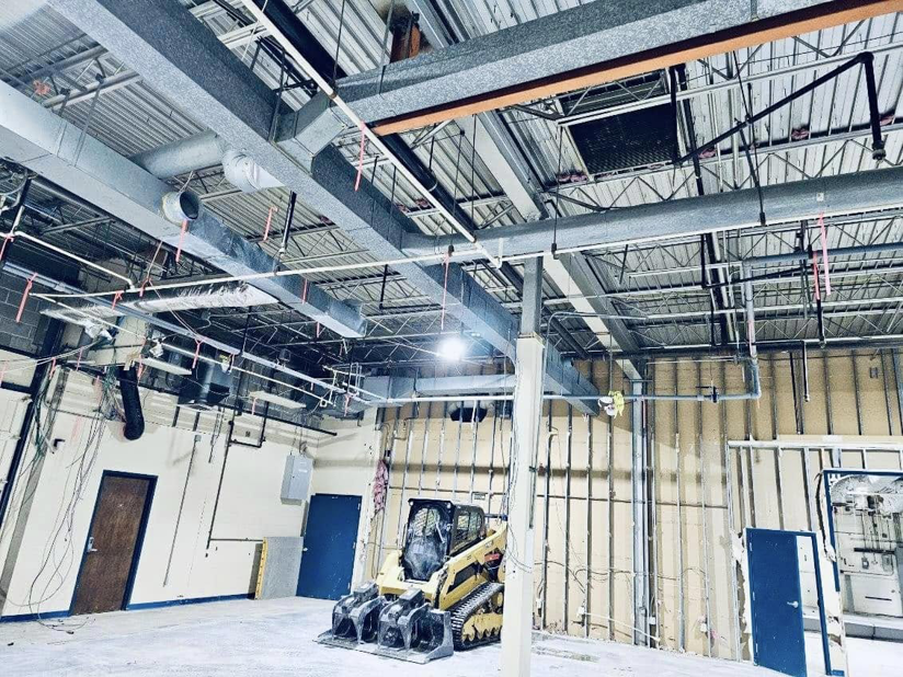 Interior demolition site with exposed ducts, wall studs, and a skid steer by Orion Demolition & Environmental Services, LLC in Albany, NY.