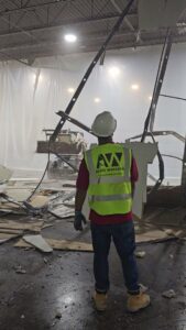 A worker overseeing interior demolition with a skid steer in the background for Allied Wrecking Boston in East Boston, MA.