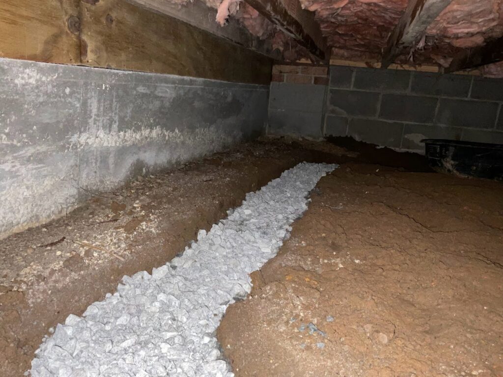 An interior French drain system being installed in a crawl space by Wetlock Waterproofing in Rock Hill, SC.