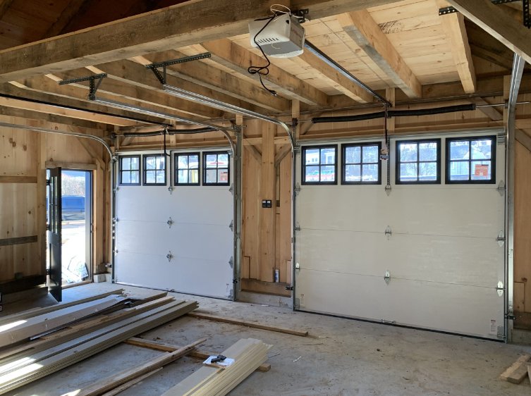 Interior view of a new construction garage with two white garage doors installed by NDI Garage Door in Plaistow, NH.