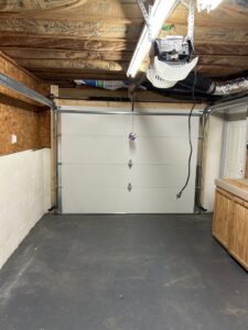 An interior view of a newly installed white garage door with visible tracks and opener by 4thgenerationsdoors in Huntington, WV.