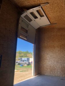 Interior view of a garage door partially open, showing tracks and exterior, installed by Vertical Door Solutions in Sheridan, WY