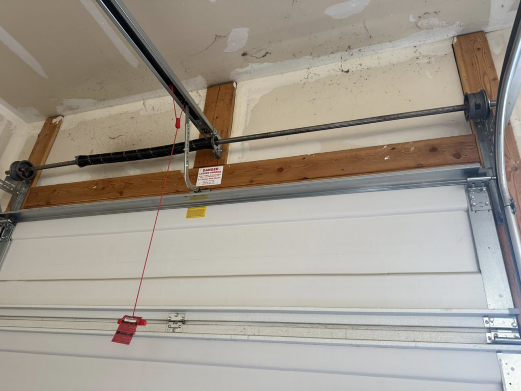 An interior view of a garage door displaying the torsion spring system and tracks by A-1 Garage Door Repair in Syracuse, UT.