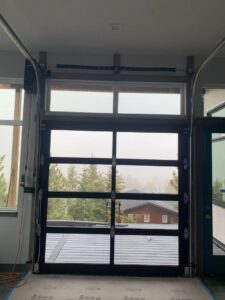 Interior view of a modern glass garage door with its tracks and opener mechanism installed by Devildog Dock N Door in Helena, MT.