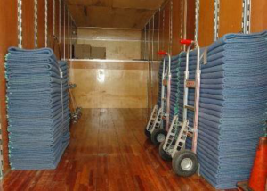 The organized interior of a moving truck with stacks of protective blankets and hand trucks, used by Movers-Moving.NET in Concord, CA.