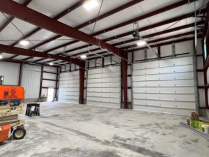 Interior of a large commercial building showcasing multiple white garage doors installed by Barrett Overhead Doors in Idaho Falls, ID.