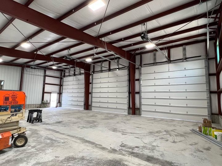 Interior of a large commercial building showcasing multiple white garage doors installed by Barrett Overhead Doors in Idaho Falls, ID.