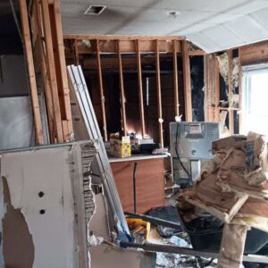 An interior room with exposed studs, insulation, and debris, indicating demolition work by HaysCo Facilities Management, Inc. in Dothan, AL.