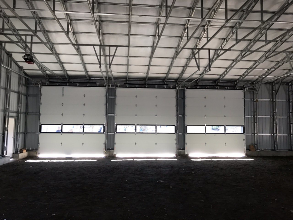Interior view of three industrial garage doors installed in a large building by Ski Door, Inc. in Center Rutland, VT.