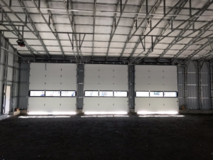Interior view of three industrial garage doors installed in a large building by Ski Door, Inc. in Center Rutland, VT.