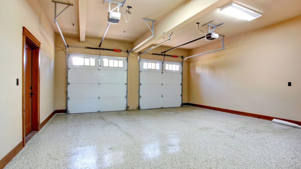 Interior view of a two-car garage with white garage doors and visible openers and tracks by Pioneer Overhead Door, Inc in Las Vegas, NV.
