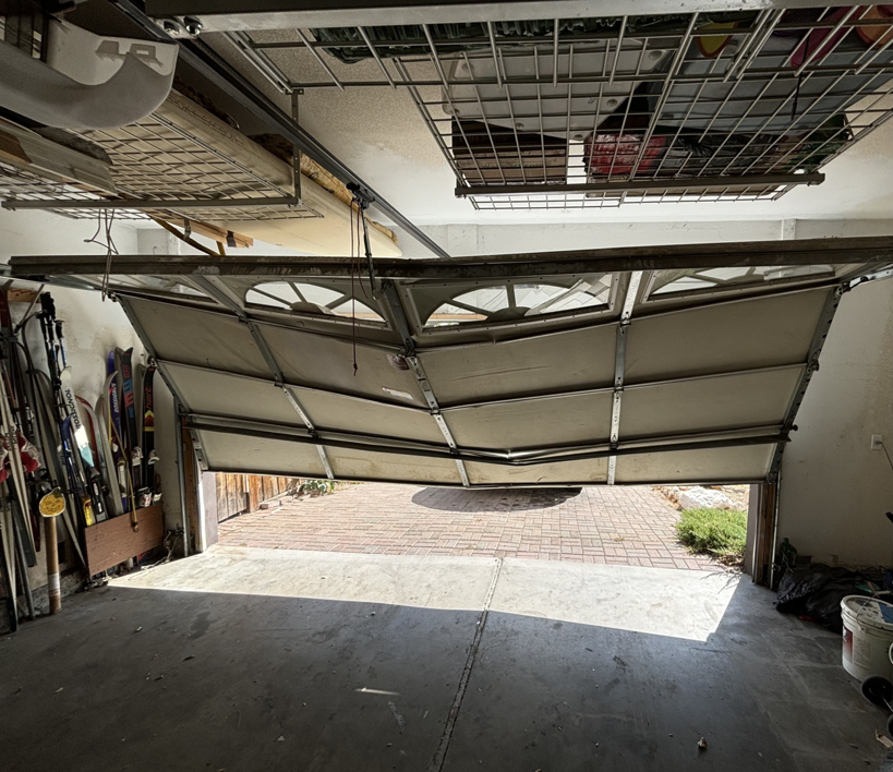 An interior view of a bent and damaged garage door, ready for repair by Summit-Overhead-Door in Sparks, NV.