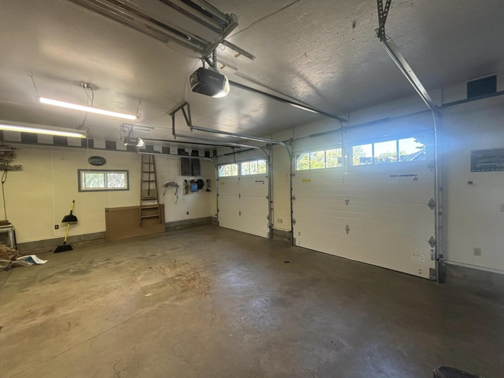 Interior view of a garage showing two installed garage doors and overhead door opener systems by Laramie Garage Doors in Laramie, WY.