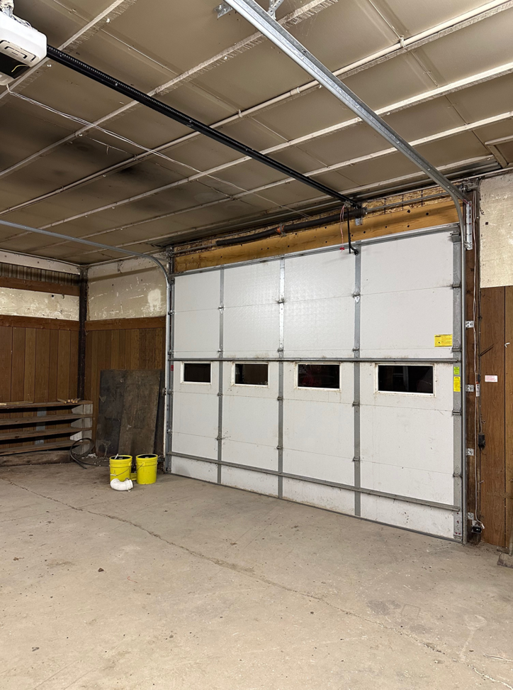 Interior view of a white sectional garage door with windows and opener installed by JTL Garage Doors in Fargo, ND.