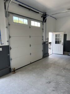 Interior view of a newly installed white sectional garage door with visible tracks and springs by Douglas Garage Door Center in East Hartford, CT.
