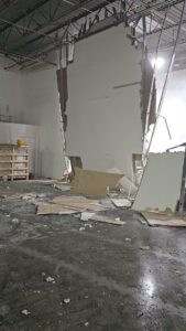 Interior wall demolition in a commercial space, with debris on the floor, by Allied Wrecking Boston in East Boston, MA.