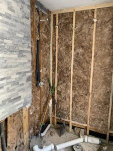 An interior wall showing exposed insulation and pipes after partial demolition by Vaquero Demolition in Lewisville, TX.