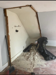 A worker cleaning up debris after interior wall demolition for water damage repair by Rival Property Maintenance in Biddeford, ME.