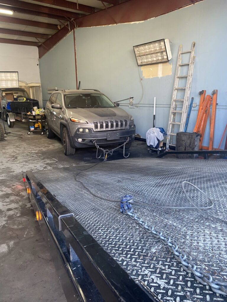 A Jeep Cherokee being loaded onto a flatbed tow truck by Black Mamba Towing & Recovery Llc in Aurora, CO.