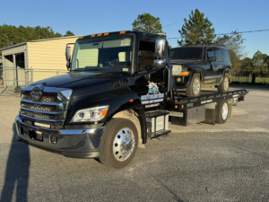A black Jeep Commander being transported on a flatbed tow truck by Southeastern Towing and Transport in Savannah, GA.