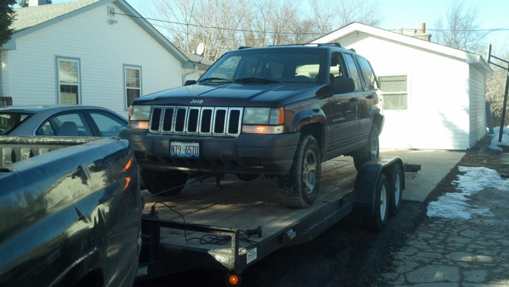 A Jeep Grand Cherokee being towed on a trailer by Jr & Sr towing and recovery in Waukegan, IL.
