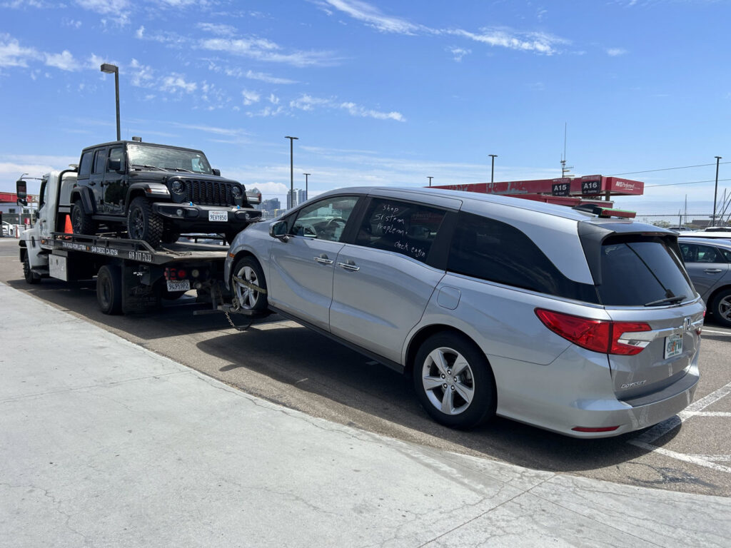 A black Jeep Wrangler on a flatbed and a silver minivan being towed by Cali kings Towing in San Diego, CA.
