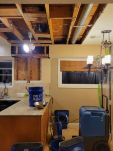 A kitchen with a removed ceiling, exposing joists, and water damage drying equipment in use by New Method Restoration in Edison, NJ.