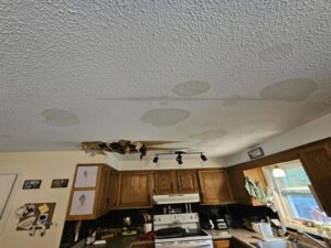 A kitchen ceiling with extensive water stains and a large hole from water damage, a job for PuroClean of Strafford County in Nottingham, NH.