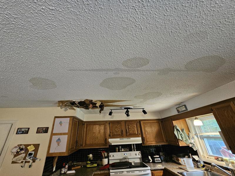 A kitchen ceiling with extensive water stains and a large hole from water damage, a job for PuroClean of Strafford County in Nottingham, NH.