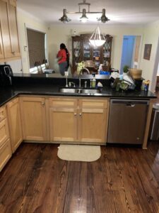 A cleaner from Brittany's Cleaning Service tidying a kitchen and dining area in Deerfield Beach, FL