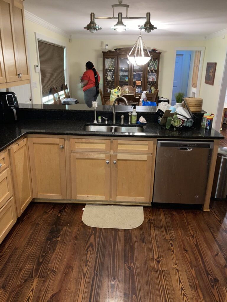 A cleaner from Brittany's Cleaning Service tidying a kitchen and dining area in Deerfield Beach, FL