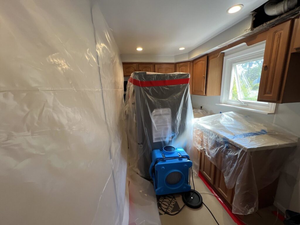 A kitchen with plastic containment and drying equipment for water damage restoration by RestoPros Hudson County in Jersey City, NJ.