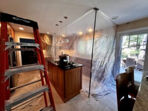A kitchen area with a plastic containment zone set up for water damage restoration by New Method Restoration in Edison, NJ.
