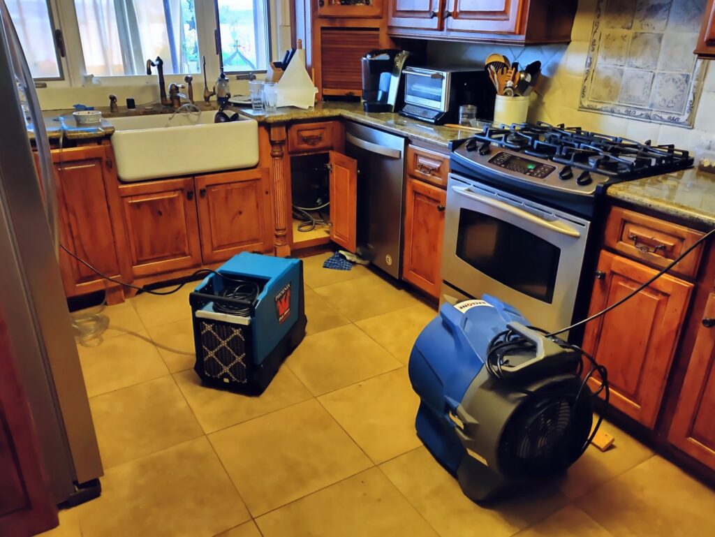Drying equipment, including a dehumidifier and air mover, in a kitchen for water damage repair by Risk Free Serv San Diego, CA