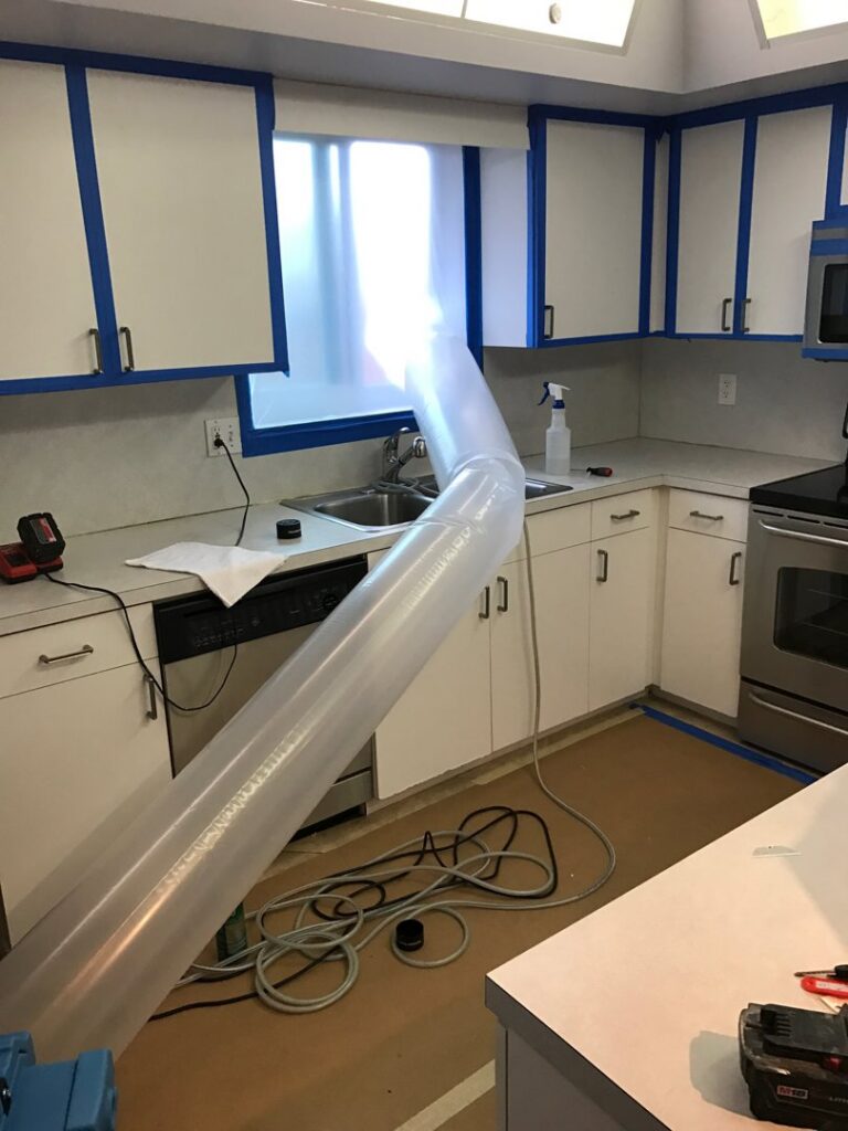 A kitchen with a flexible duct and blue tape, indicating a drying setup for water damage restoration by Southcoast Cleaning Solutions & Restoration in Fall River, MA.