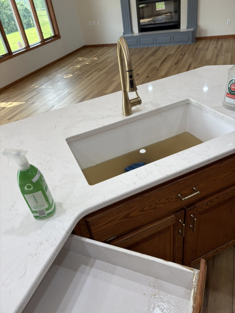 Kitchen sink with dirty water and cleaning supplies, showing work in progress by Divine Cleaning in Fargo, ND.